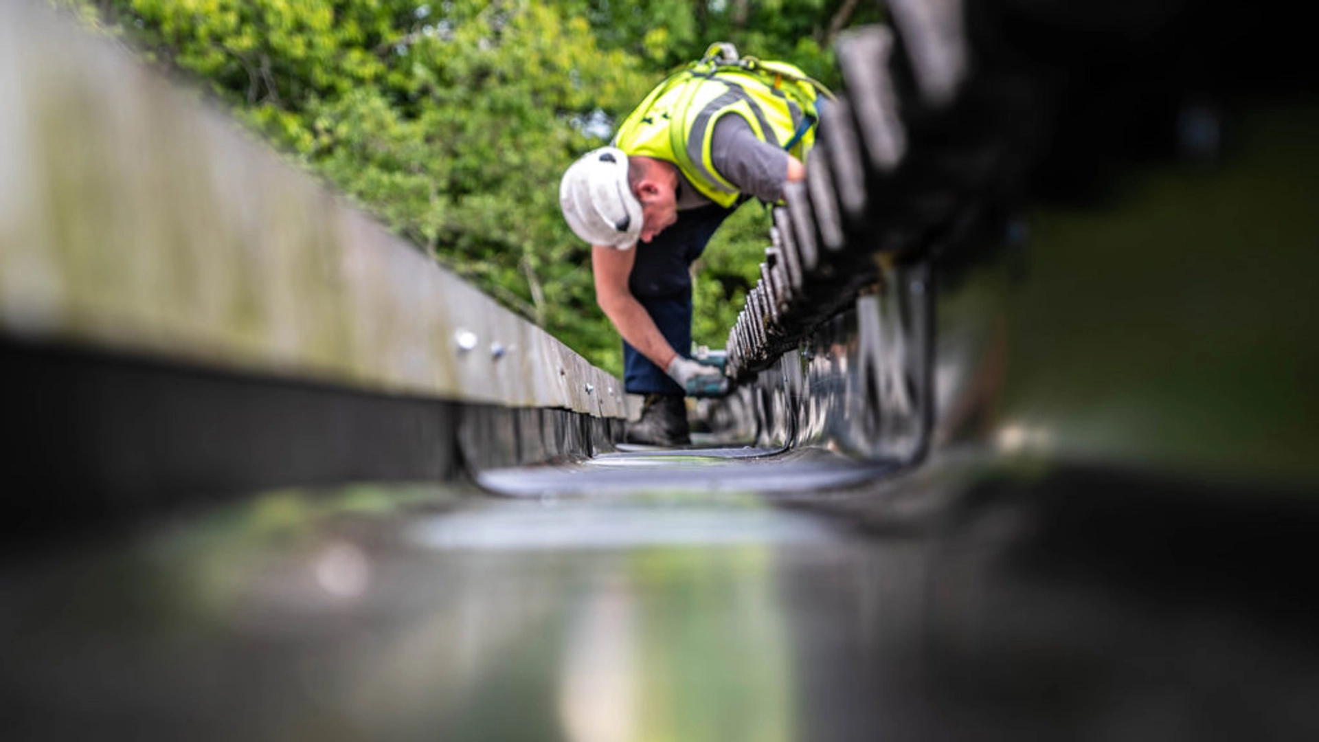Technician inspecting and clearing industrial guttering